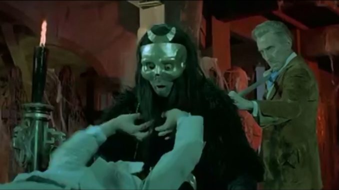Peter Cushing as Van Helsing impales a vampire wearing a golden mask