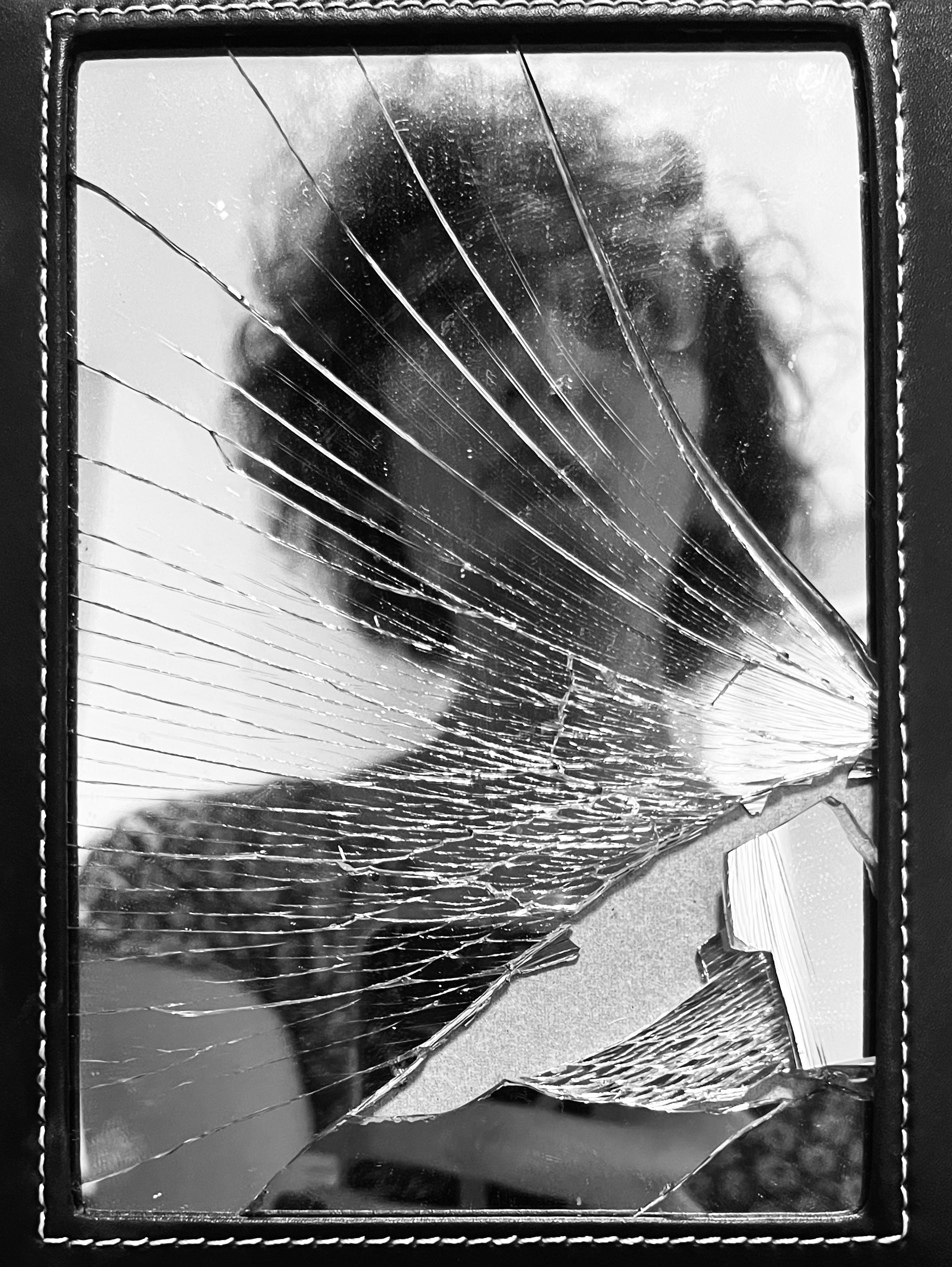 A picture of me reflected in a small mirror. The glass is cracked. I'm looking up. The image is in black and white